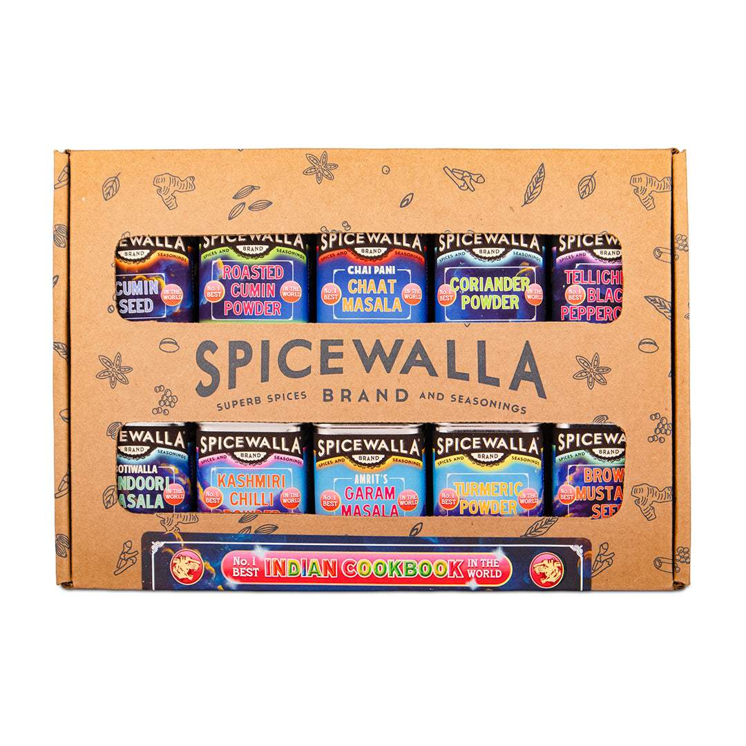 Spicewalla Spice Box set containing 12 small spice jars arranged in two rows on a brown cardboard box, with an Indian Cookbook included. The box features illustrations of spices and the brand name 'Spicewalla' prominently displayed.
