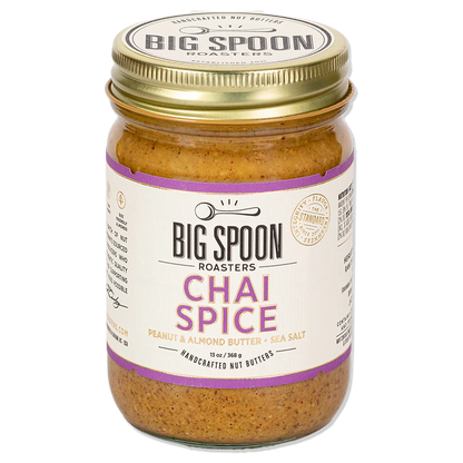 A glass jar of Big Spoon Roasters Chai Spice peanut and almond butter with a gold metal lid and a white label with purple text, set against a plain white background.