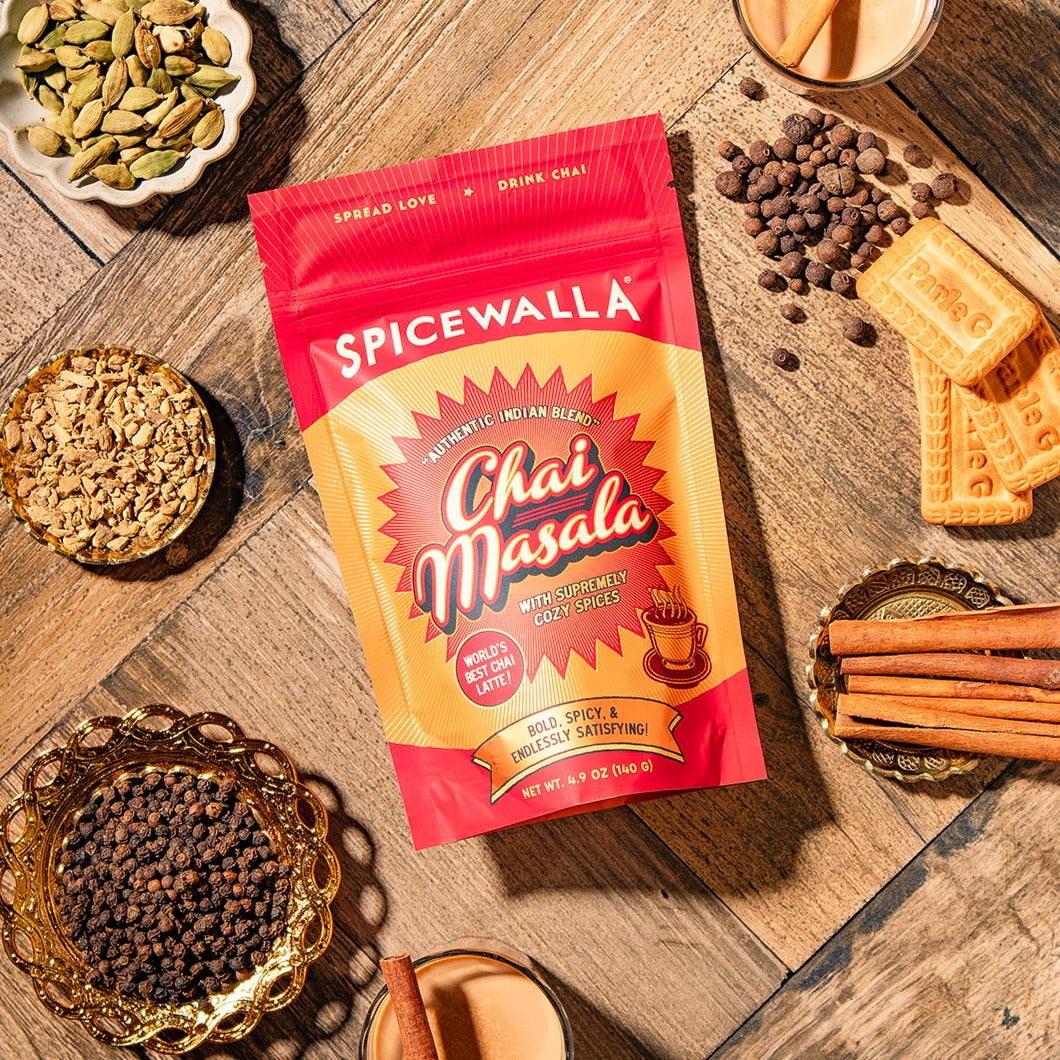 Spicewalla Chai Masala package on a wooden surface with spices and tea.