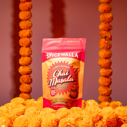Spicewalla Chai Masala package surrounded by marigolds on a pink background