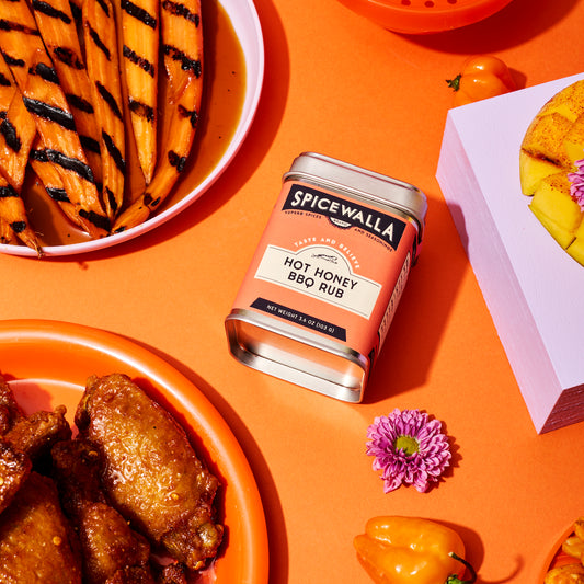 Spicewalla Hot Honey BBQ Rub displayed around grilled foods on orange background