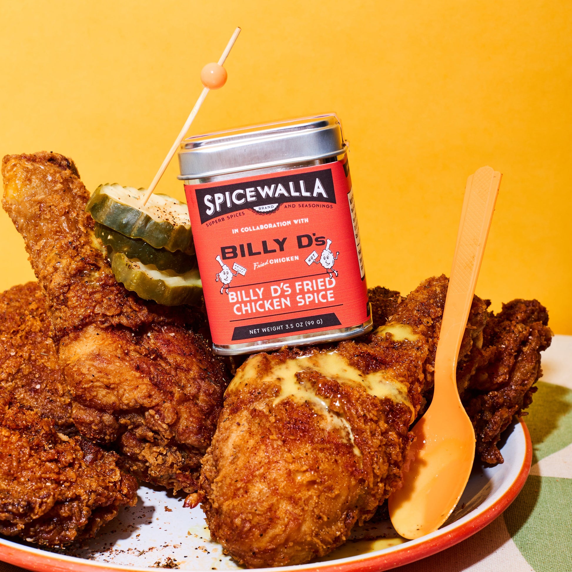 Spicewalla Billy D's Chicken Spice tin on top of a piece of fried chicken with an orange background