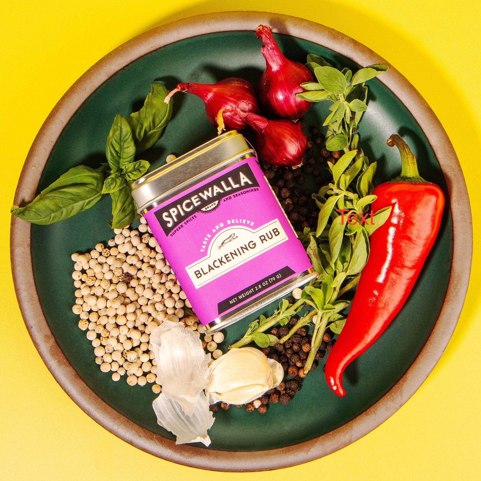 Spicewalla Blackening Rub can surrounded by spices and herbs on a green plate with a yellow background