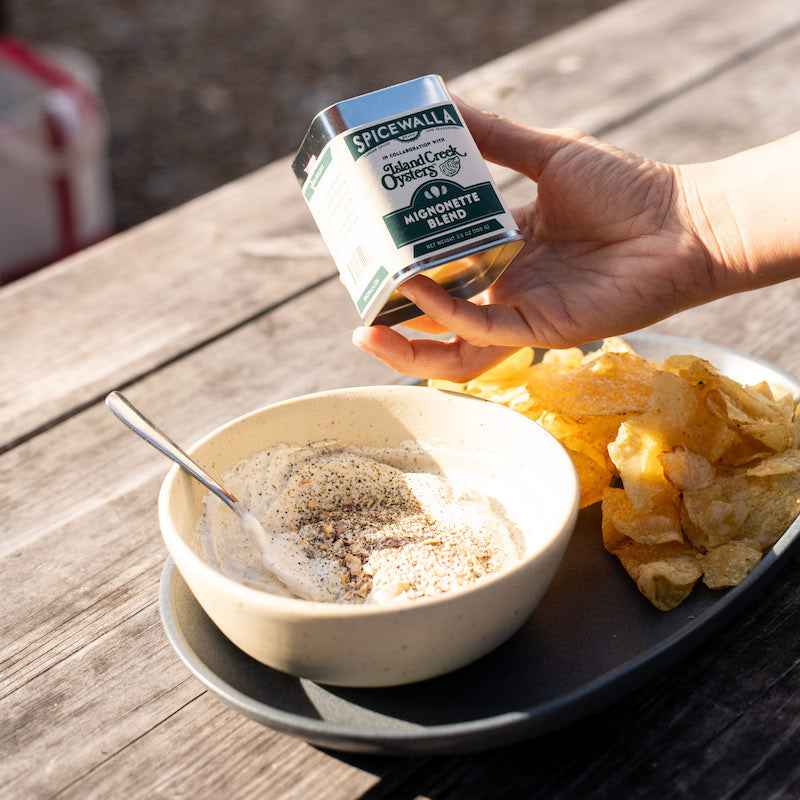 Spicewalla Mignonette Blend tin held above dip and chips