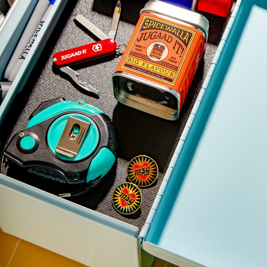 Open drawer with stationery items including a Swiss Army knife, tape measure, and Spice World Juggaad It can.