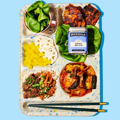 Notebook with food items and a can of Spicewalla Korean BBQ Rub on a blue background