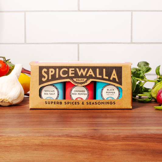Spicewalla spice set on a wooden surface with vegetables in the background