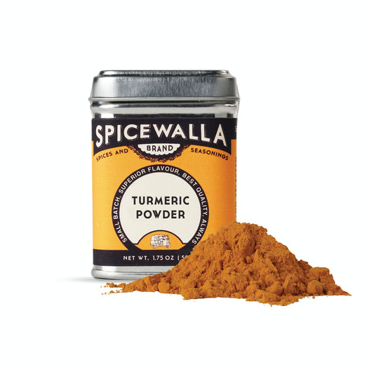 Spicewalla turmeric powder canister with turmeric powder spilling out on a white background