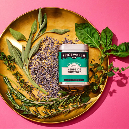 Spicewalla Herbs de Provence packaging on a gold plate with herbs on a pink background